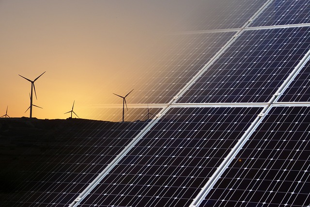 Renewable energy sources at night: Illuminated solar panels and wind turbines.